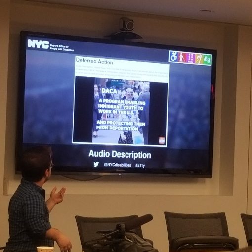 Jonathan, a little person stands in front of a tv screen with a slide describing how to make social media accessible using ALT Text.